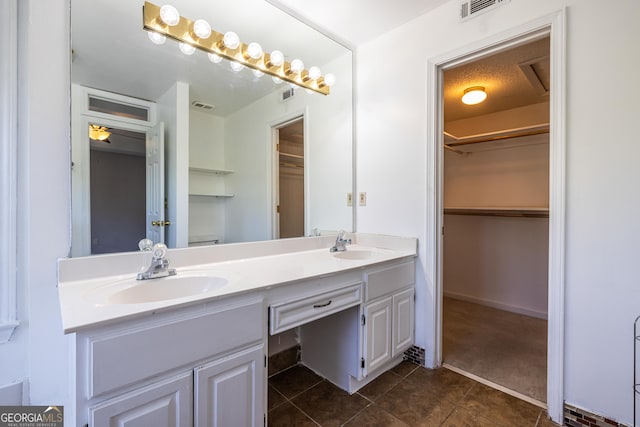 full bath with a sink, tile patterned floors, double vanity, and visible vents