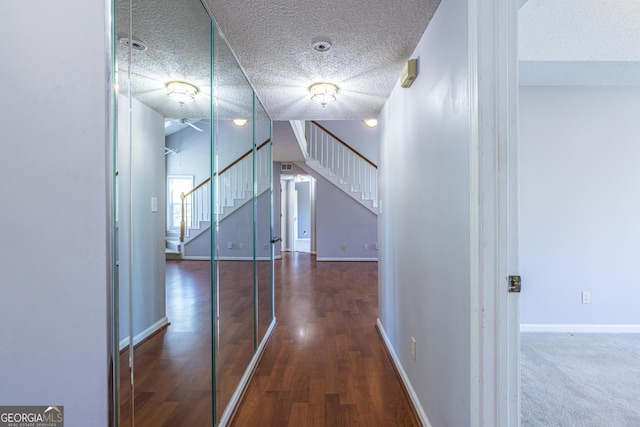 hallway featuring baseboards, a textured ceiling, stairs, and wood finished floors