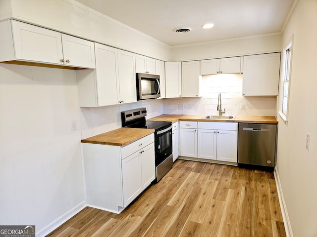 802 Colquitt Cir, Albany, GA 31707 - kitchen with light wood finished floors, a sink, stainless steel appliances, crown molding, and butcher block counters