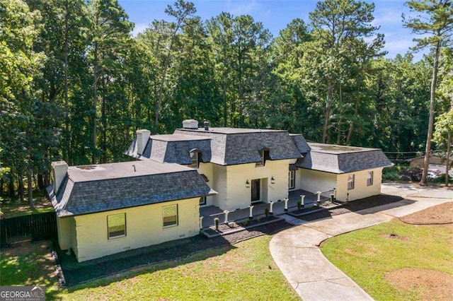 2023 Stoneleigh Dr, Stone Mountain, GA 30087 - view of front of home with a chimney, fence, a shingled roof, mansard roof, and a front lawn