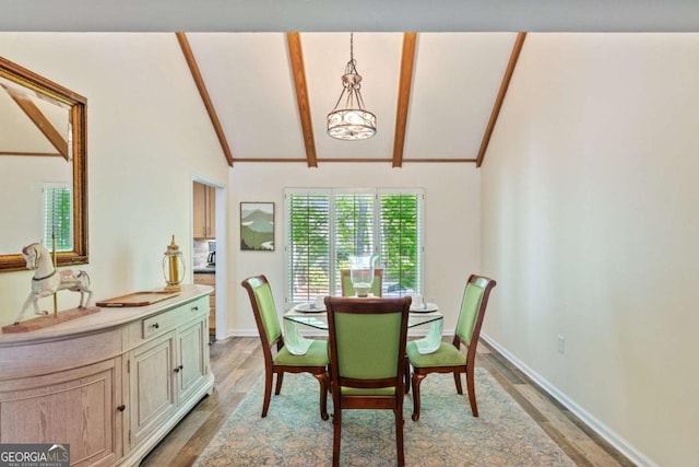 dining space with light wood finished floors, vaulted ceiling with beams, and baseboards
