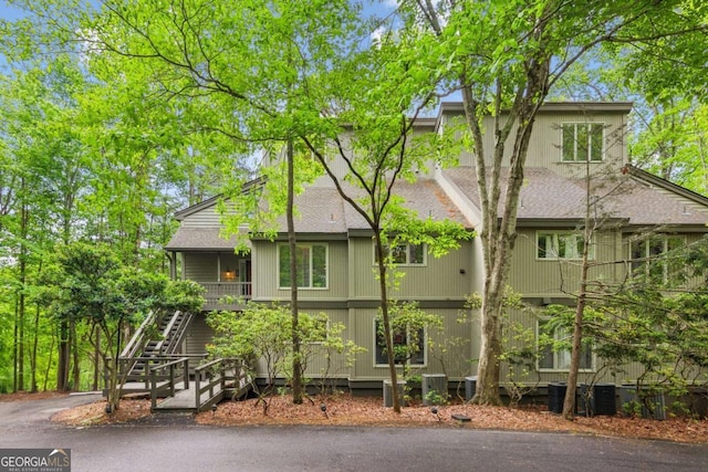 exterior space with roof with shingles and stairs