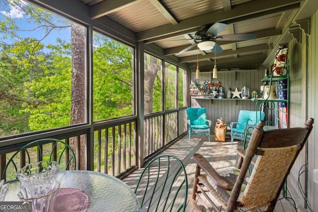 sunroom featuring a ceiling fan and beamed ceiling