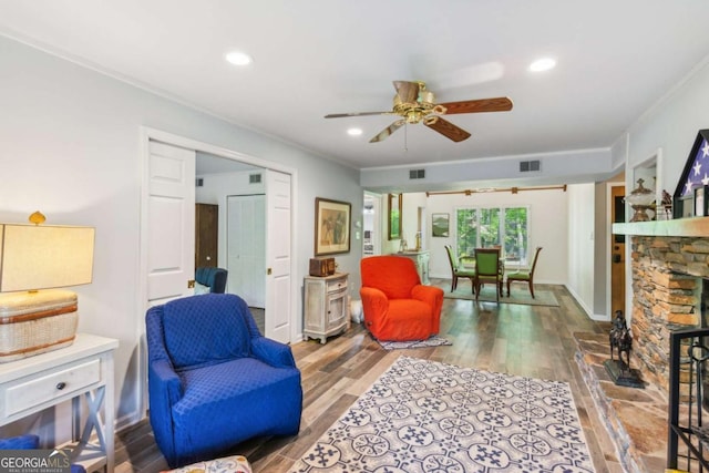living room with ornamental molding, visible vents, ceiling fan, and wood finished floors