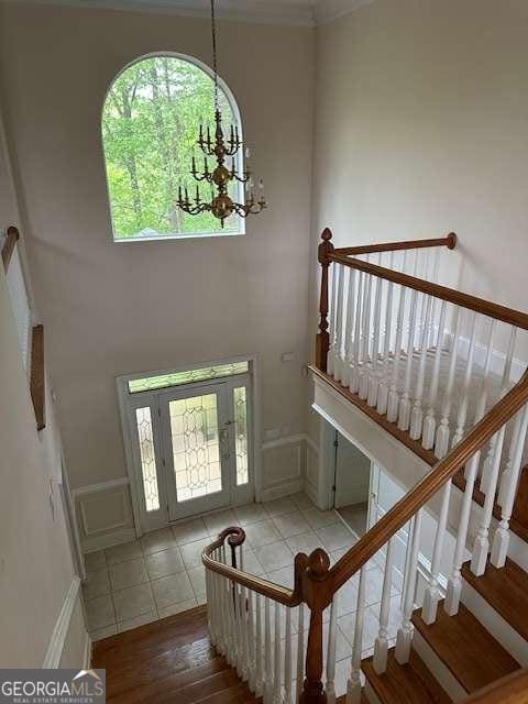 8010 Scudder Way, Ball Ground, GA 30107 - foyer entrance with a chandelier, wood finished floors, stairway, a decorative wall, and a high ceiling