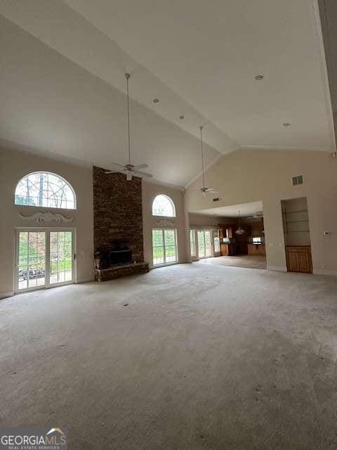 8010 Scudder Way, Ball Ground, GA 30107 - unfurnished living room featuring carpet flooring, a ceiling fan, high vaulted ceiling, and a stone fireplace