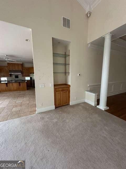 8010 Scudder Way, Ball Ground, GA 30107 - unfurnished living room with decorative columns, a high ceiling, ornamental molding, light colored carpet, and a ceiling fan