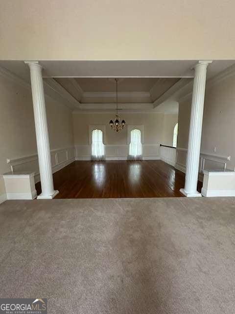 8010 Scudder Way, Ball Ground, GA 30107 - unfurnished dining area with decorative columns, a tray ceiling, crown molding, carpet, and wood finished floors