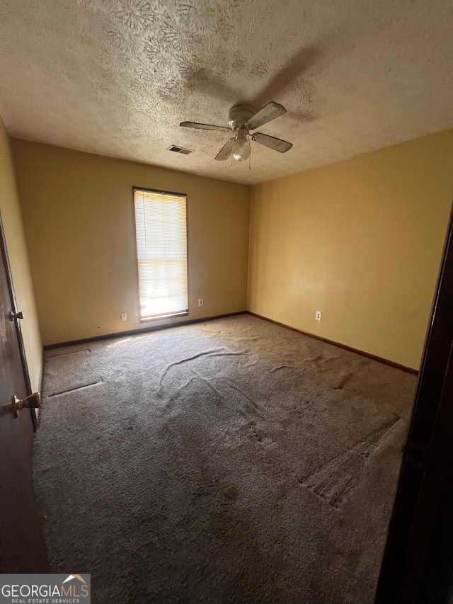 unfurnished room with visible vents, ceiling fan, carpet floors, and baseboards