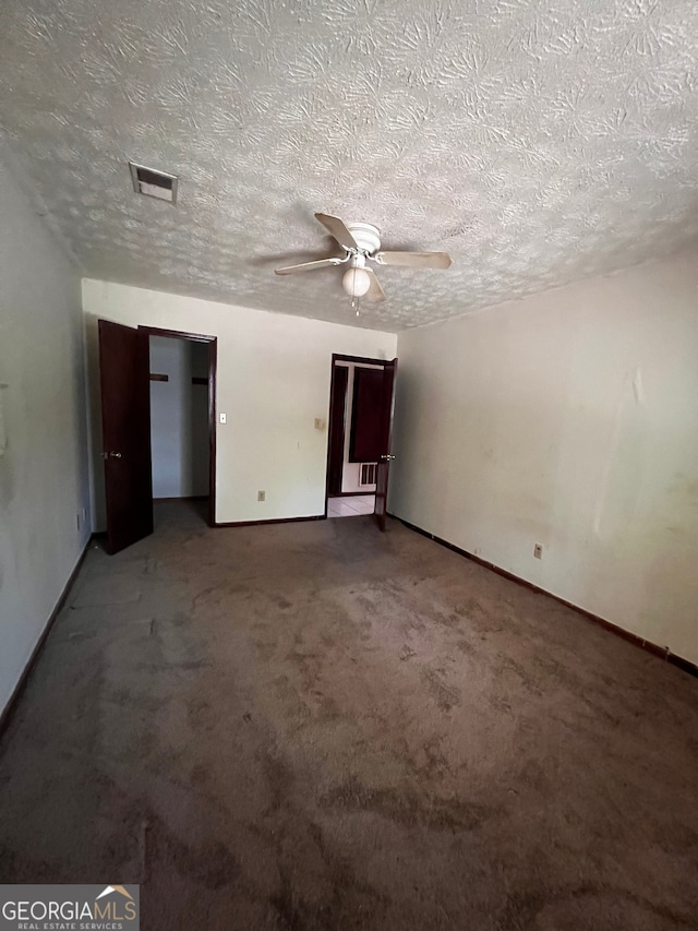 unfurnished room featuring ceiling fan, carpet flooring, baseboards, visible vents, and a textured ceiling