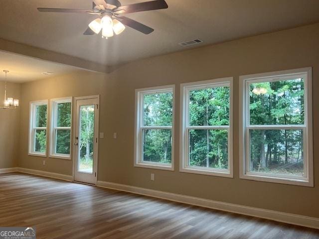 doorway to outside featuring baseboards, visible vents, wood finished floors, and ceiling fan with notable chandelier