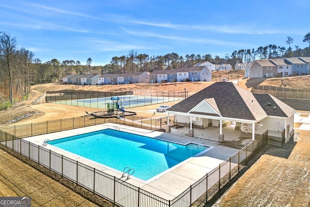 community pool with a patio, fence, and a residential view