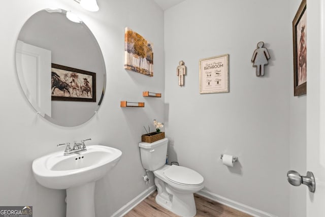 half bathroom with a sink, wood finished floors, toilet, and baseboards