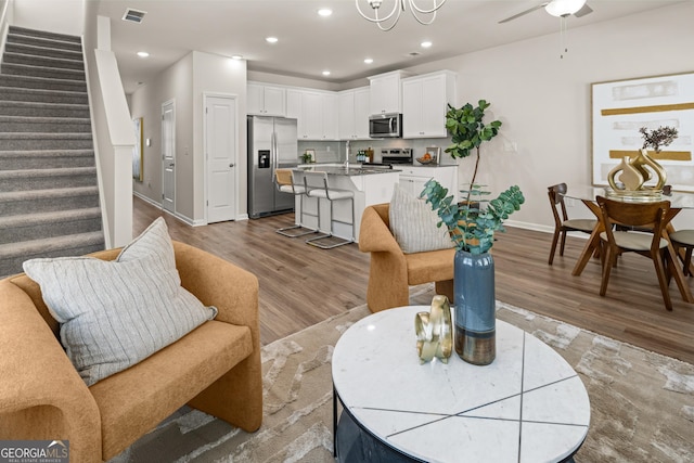 living room with baseboards, stairs, light wood-style flooring, and visible vents