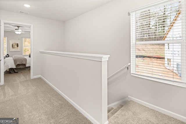 hall with baseboards, visible vents, carpet flooring, and an upstairs landing