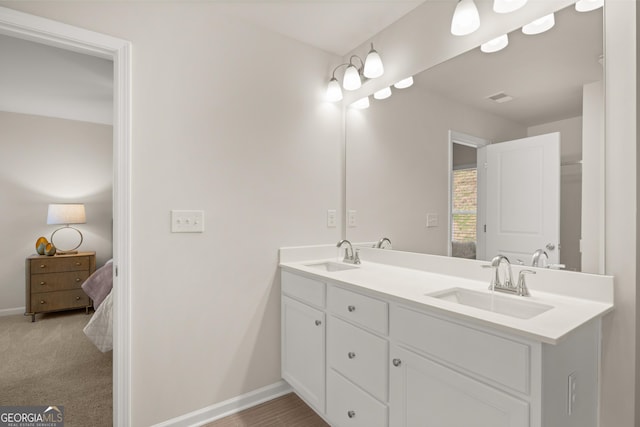 ensuite bathroom featuring double vanity, baseboards, a sink, and ensuite bathroom