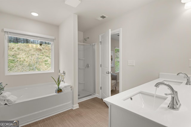 full bathroom featuring double vanity, a shower stall, a bath, and visible vents
