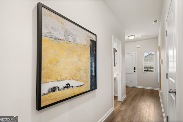 corridor with visible vents, baseboards, and wood finished floors