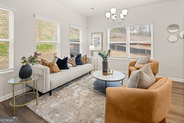 living area with baseboards, wood finished floors, and a notable chandelier
