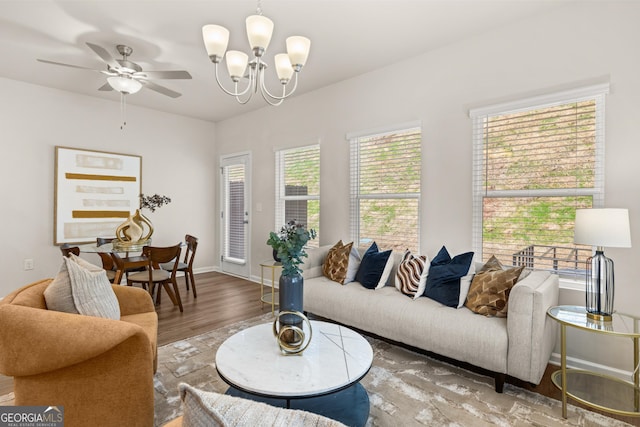 living area featuring baseboards, ceiling fan with notable chandelier, and wood finished floors