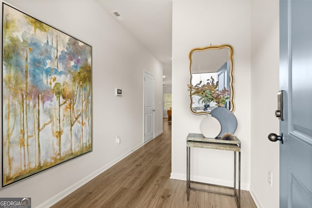 hallway featuring baseboards, visible vents, and wood finished floors
