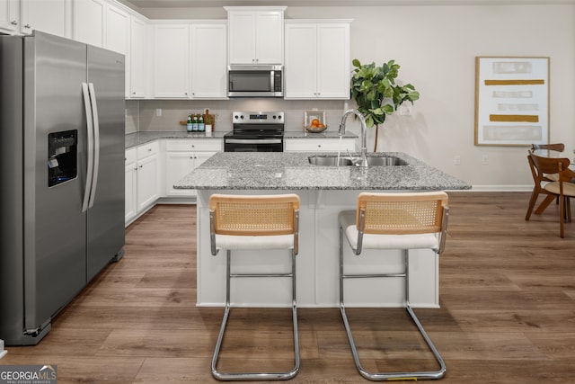 kitchen with a sink, appliances with stainless steel finishes, baseboards, and wood finished floors