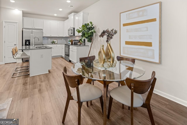 dining space featuring baseboards, recessed lighting, and light wood finished floors