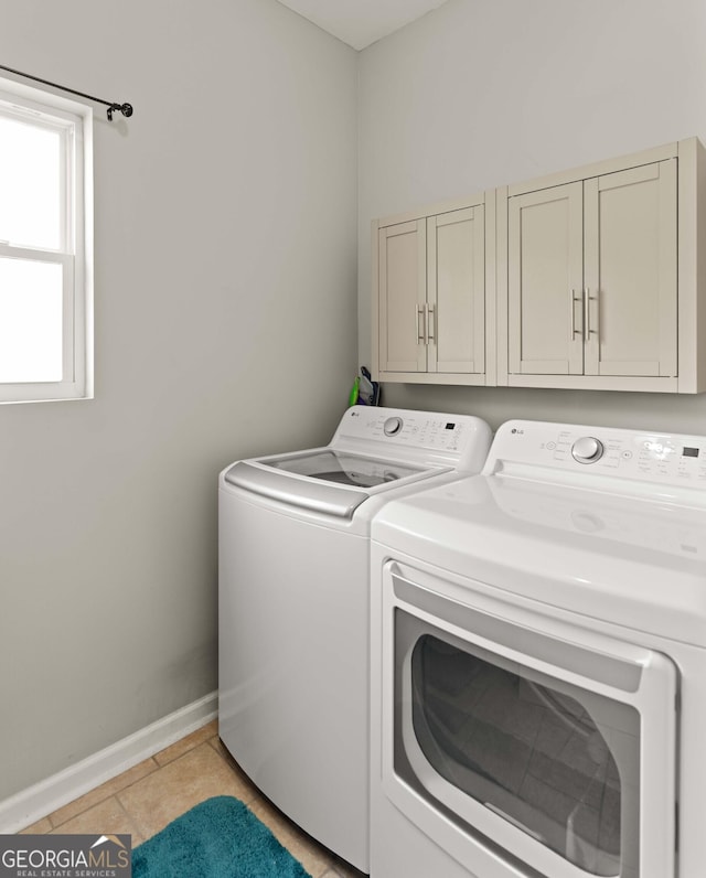 washroom with light tile patterned flooring, cabinet space, independent washer and dryer, and baseboards