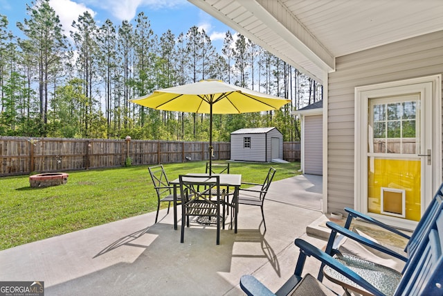 view of patio / terrace featuring an outdoor fire pit, a fenced backyard, an outbuilding, a storage shed, and outdoor dining space