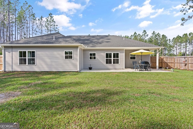 rear view of house with a patio, fence, a shingled roof, and a yard