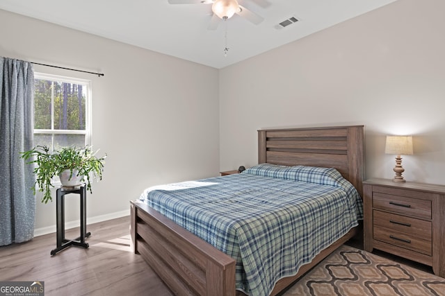 bedroom with baseboards, visible vents, wood finished floors, and a ceiling fan
