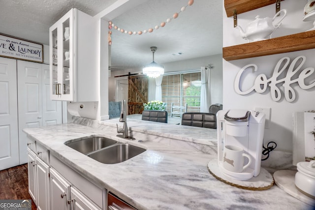 1029 Megan Ct, Sugar Hill, GA 30518 - kitchen featuring a sink, a textured ceiling, white cabinetry, glass insert cabinets, and a barn door