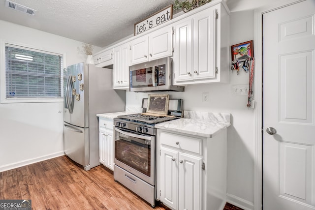 1029 Megan Ct, Sugar Hill, GA 30518 - kitchen with appliances with stainless steel finishes, white cabinetry, light wood-style floors, baseboards, and light stone countertops