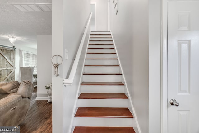 1029 Megan Ct, Sugar Hill, GA 30518 - staircase featuring wood finished floors, a barn door, baseboards, and a textured ceiling