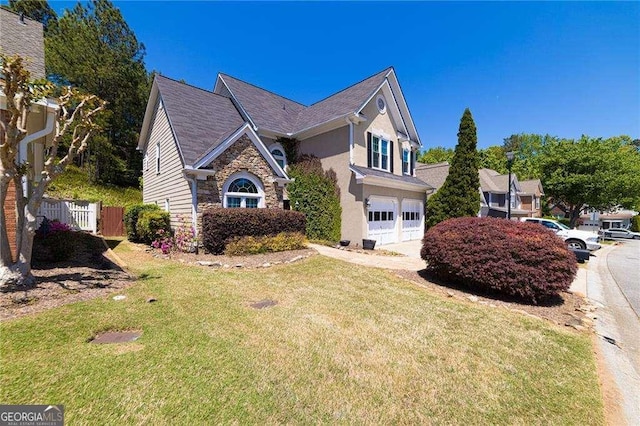 view of front facade with a garage, fence, a front lawn, stone siding, and stucco siding