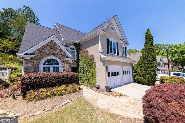 view of front of property with stucco siding, driveway, stone siding, and a garage