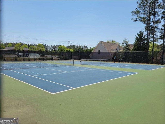view of tennis court with community basketball court and fence