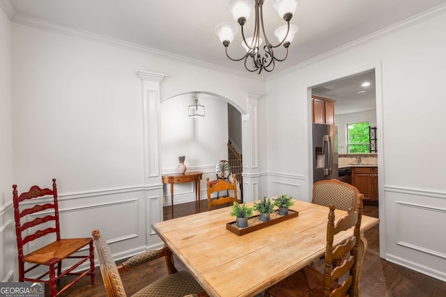dining room featuring ornamental molding, a notable chandelier, dark wood-style floors, and arched walkways