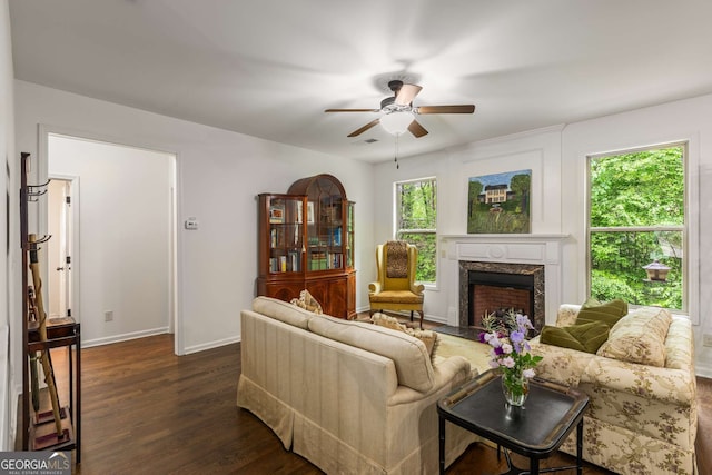 living area featuring baseboards, a fireplace, dark wood-style floors, visible vents, and a ceiling fan