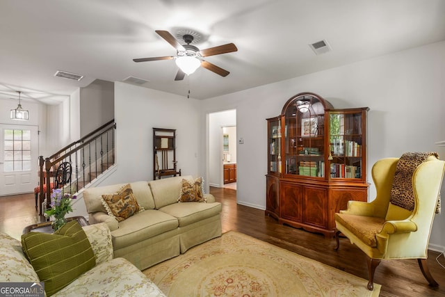 living room with visible vents, wood finished floors, and ceiling fan
