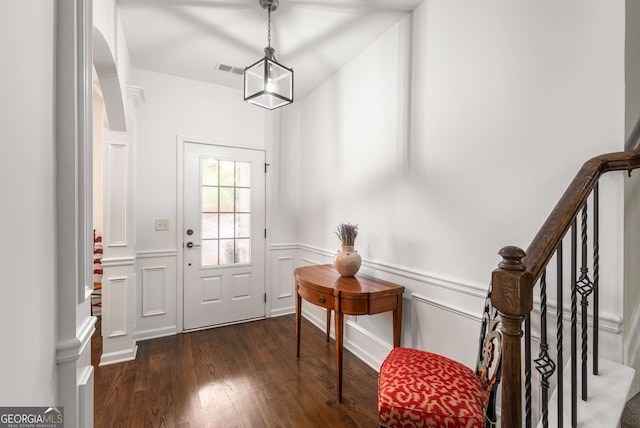 doorway to outside featuring stairs, visible vents, a decorative wall, wainscoting, and wood finished floors