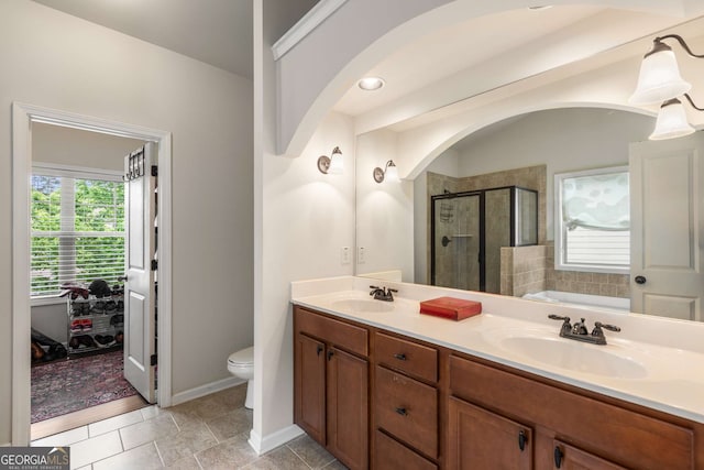 bathroom featuring a stall shower, toilet, double vanity, and a sink