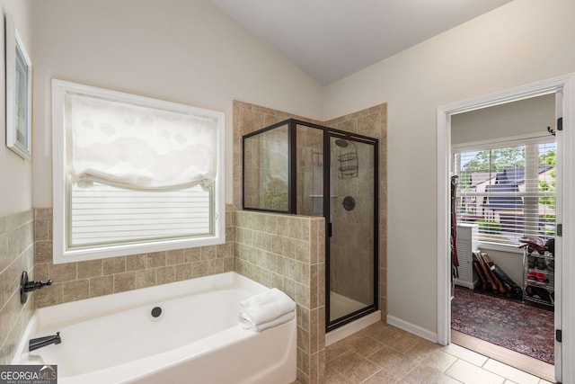 bathroom with a garden tub, a shower stall, vaulted ceiling, and tile patterned floors