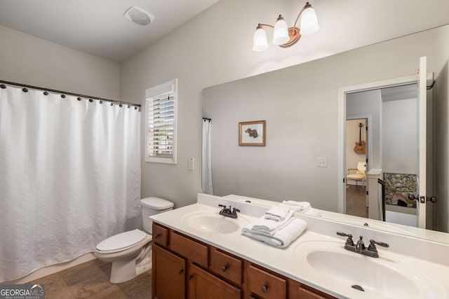 bathroom featuring curtained shower, toilet, double vanity, and a sink