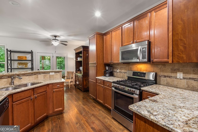kitchen featuring decorative backsplash, appliances with stainless steel finishes, brown cabinets, dark wood-style flooring, and a sink