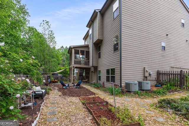 rear view of house with fence, central air condition unit, and a garden
