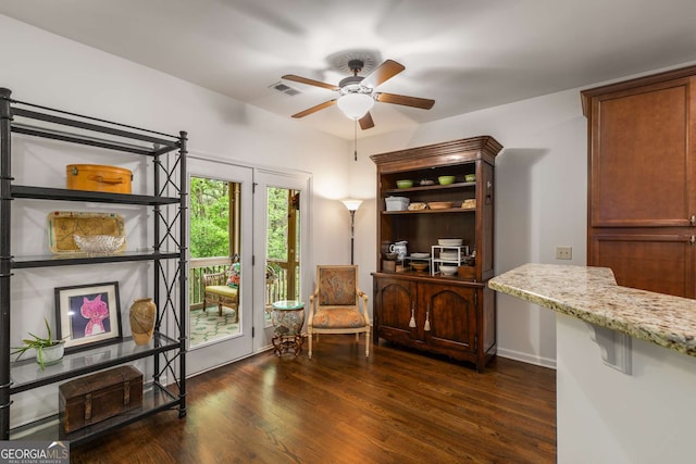 living area with visible vents, a ceiling fan, and dark wood-style floors