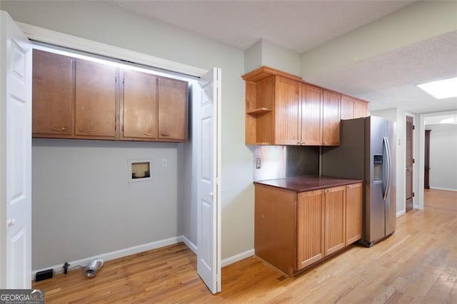 clothes washing area featuring hookup for a washing machine, cabinet space, baseboards, and light wood-style floors