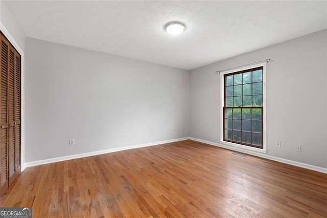unfurnished bedroom with a closet, visible vents, baseboards, and light wood-style floors