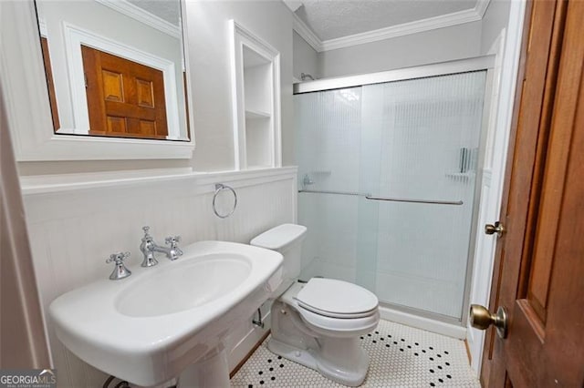 bathroom with toilet, crown molding, a stall shower, and a sink